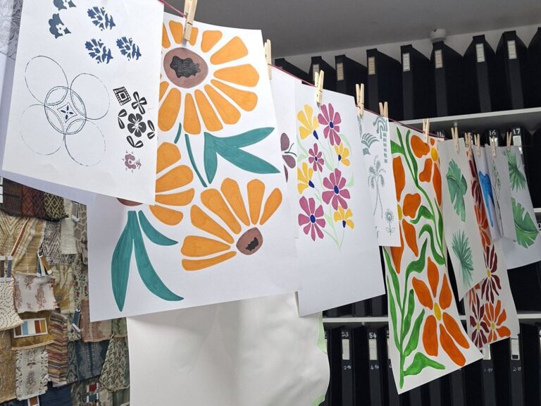 Proposte collection workshop with painted floral artwork hanging from a line